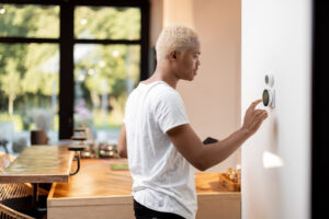 A man adjusting his thermostat on the wall in his home